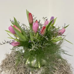 Pink and purple tulips in a glass vase with airy filler