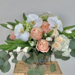 Peach roses and white orchids in a glass vase