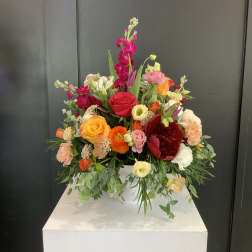 Colorful mixed flower arrangement in a white container