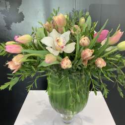 Pink tulips and a white orchid in a green glass vase