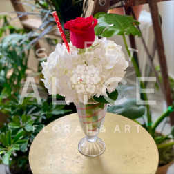 Red rose in a clear glass vase with white hydrangeas