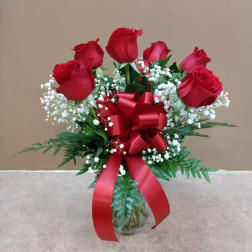 Bouquet of red roses with baby's breath in a glass vase and red ribbon
