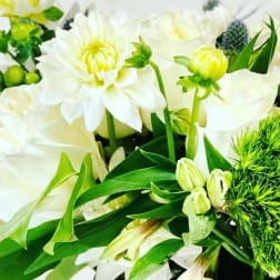 White dahlias and lilies with green buds and foliage