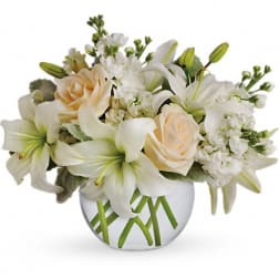 White lilies and pale peach roses arranged in a round glass vase