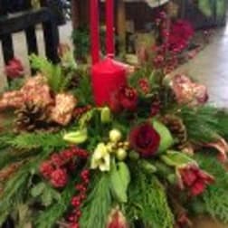 Large floral arrangement with red candles and red, peach, and white flowers