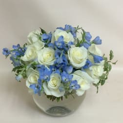 White roses and blue flowers in a clear glass vase