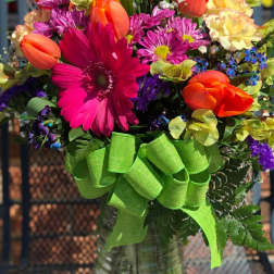 Colorful mixed bouquet in a glass vase with a green ribbon