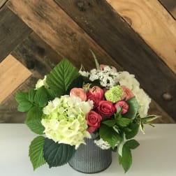 Pink roses and hydrangeas arranged in a metal container