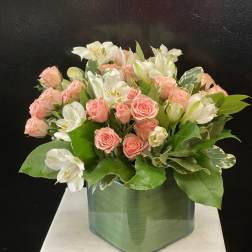 Pink roses and white alstroemeria arranged in a green glass vase