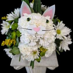 White floral arrangement styled as a cat face with pink ears and whiskers