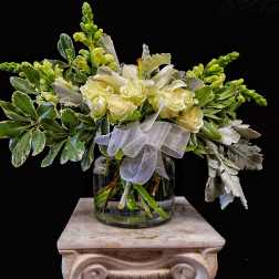 White roses in a glass vase with a sheer ribbon