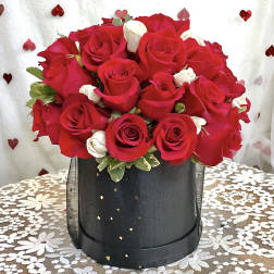 Red and white roses arranged in a black hatbox