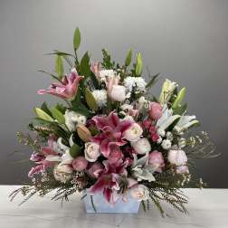 Pink and white lilies and roses arranged in a low rectangular vase