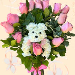 Pink roses and a white teddy bear made of carnations in a glass vase