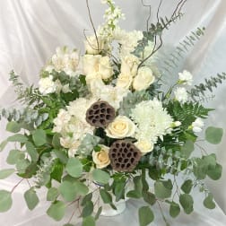 White roses and chrysanthemums in a white vase with eucalyptus and lotus pods