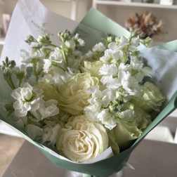 Bouquet of white roses and pale green blooms wrapped in mint paper
