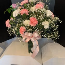 Pink and white carnations with baby's breath in a vase, tied with a pink ribbon