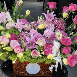 Large pink and yellow floral arrangement in a decorative wooden container