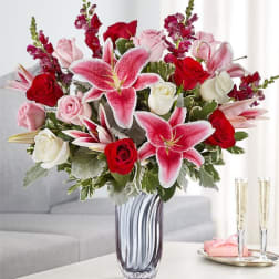 Bouquet of pink lilies and red and white roses in a glass vase
