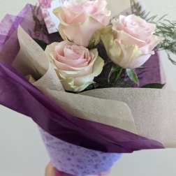 Bouquet of pale pink roses wrapped in purple and beige paper