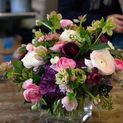Mixed pink, white, and purple flowers arranged in a clear glass vase