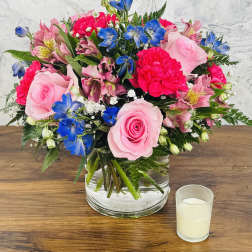 Pink and blue mixed flower arrangement in a clear glass vase