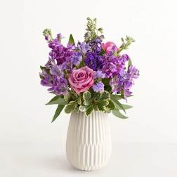 Purple and pink flower arrangement in a white vase