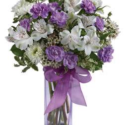 Purple and white bouquet in a clear square vase with a ribbon