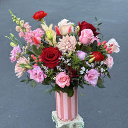 Mixed bouquet of pink and red flowers in a striped pink vase