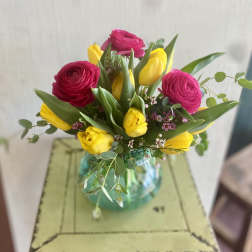 Bouquet of pink ranunculus and yellow tulips in a glass vase