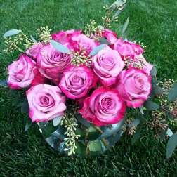Pink roses arranged in a clear glass bowl with eucalyptus accents