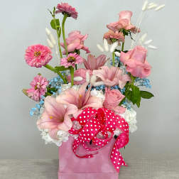 Pink floral arrangement in a pink box with a polka-dot ribbon