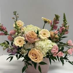 Pastel floral arrangement in a pink round box with roses, gerberas, and hydrangea