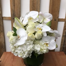 White orchid and rose arrangement in a dark glass vase