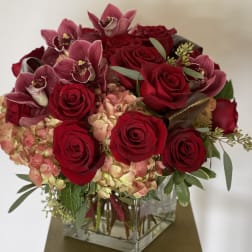 Red roses and pink orchids in a square glass vase