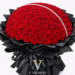 Large dome bouquet of red roses with a pearl strand and black wrapping paper.