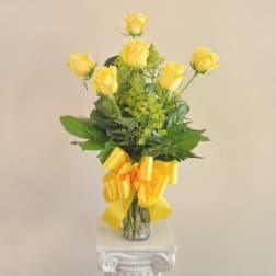 Yellow roses in a clear glass vase with a yellow ribbon