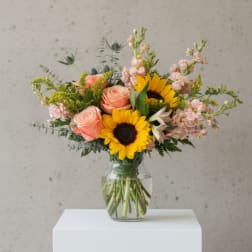 Bouquet of sunflowers and peach roses in a clear glass vase