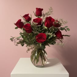 Arrangement of red roses with white filler flowers in a round clear glass vase