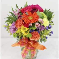 Colorful mixed flower bouquet in a glass vase with ribbon