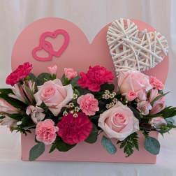 Pink roses and carnations arranged in a heart-shaped box with wicker hearts