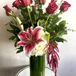 Bouquet of red roses and pink lilies in a tall green vase