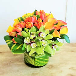 Bouquet of orange tulips and green orchids in a striped vase