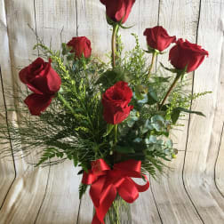 Red roses in a clear glass vase with a red ribbon