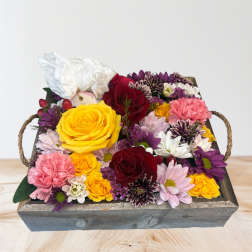 Mixed bouquet of roses and daisies in a wooden tray