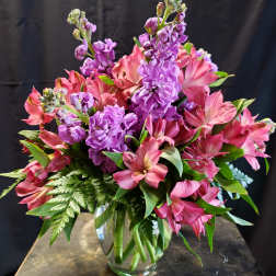 Pink and purple flowers arranged in a clear glass vase
