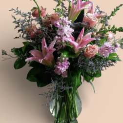 Pink lilies and roses in a clear glass vase