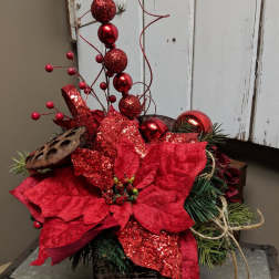Red poinsettia arrangement with glittery ornaments and pine accents
