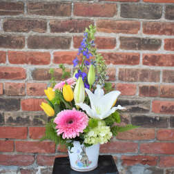 Mixed bouquet in a white vase with pink gerbera daisies, yellow tulips, and a white lily