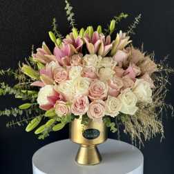 Pink and white roses with lilies in a gold vase